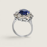 4.5ct Oval Cut Center sapphire surrounded by 12 Round Cut Stones of 2.5 TCW. Center stone size: 12x10mm F233-SAP-CZ-14K