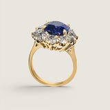 4.5ct Oval Cut Center sapphire surrounded by 12 Round Cut Stones of 2.5 TCW. Center stone size: 12x10mm F233-SAP-CZ-14K